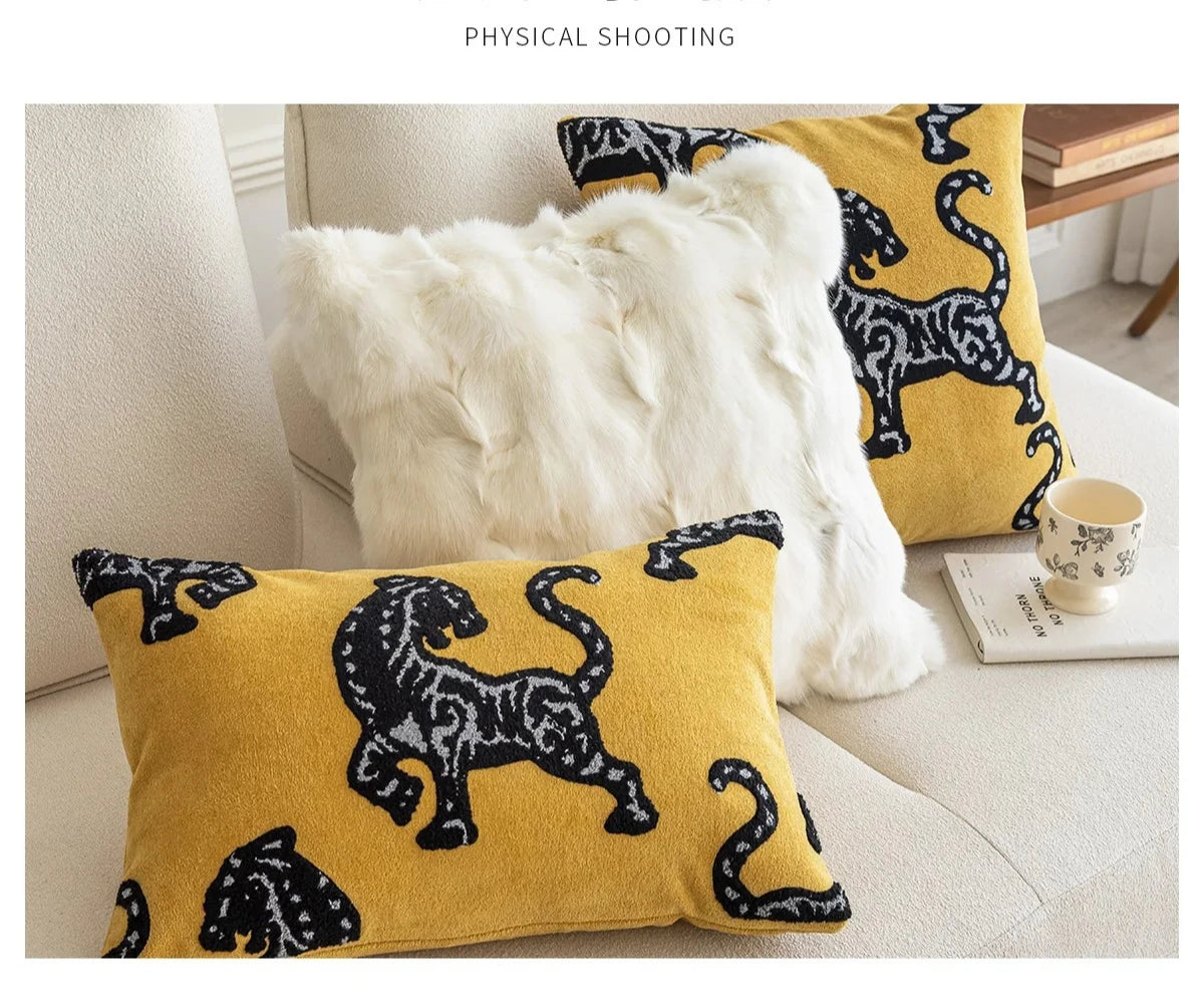 Yellow pillows with black animal patterns on a couch. Modern minimalist embroidered pillow cover for living room decor