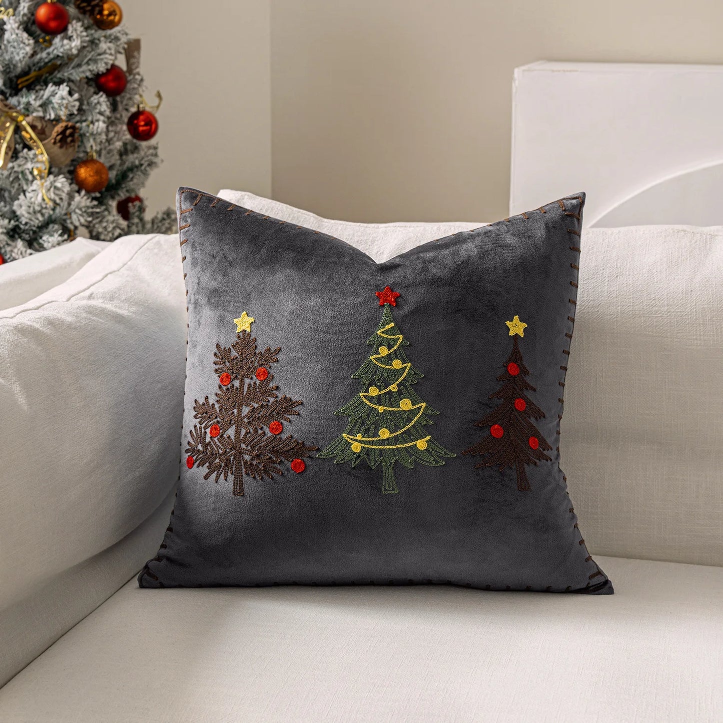 Gray pillow with embroidered Christmas trees on a white couch