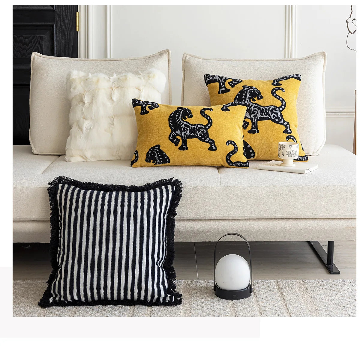 Decorative pillows on a sofa with a black and white striped pillow in the foreground. Modern minimalist embroidered pillow cover for living room decor.