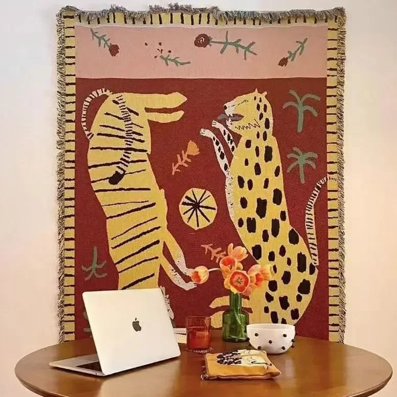 Decorative blanket with animal design on a table with a laptop and other items. Leopard design boho home decor blanket, decorative woven tapestry for living room or bedroom