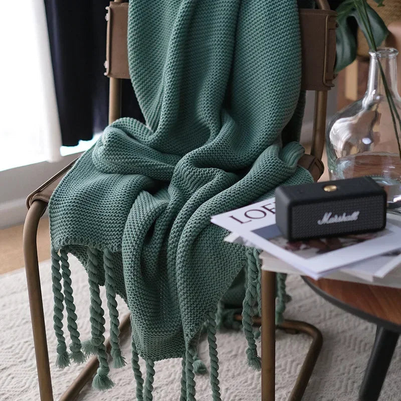 Green knitted blanket draped over a chair with a Marshall speaker and magazine underneath.