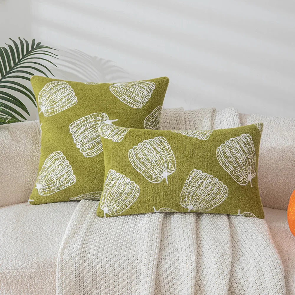 Green pillows with white patterns on a beige couch. Cozy fall pumpkin pillow cover for living room or bedroom