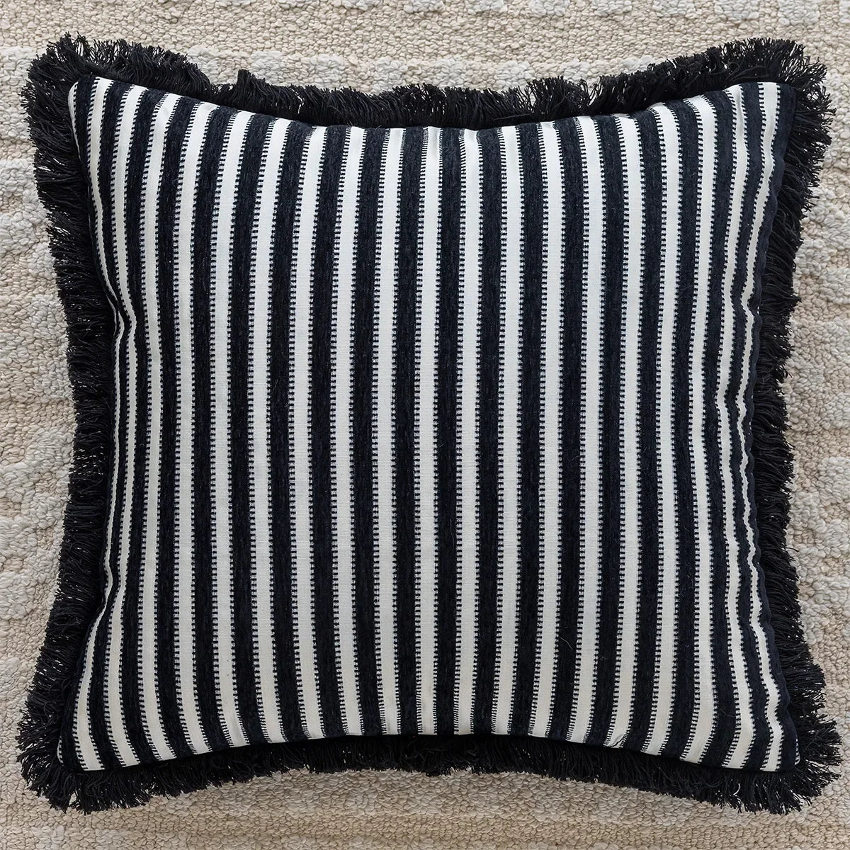 Striped pillow with black and white pattern and frayed edges on a textured surface. embroidery throw pillow cover in boho modern style