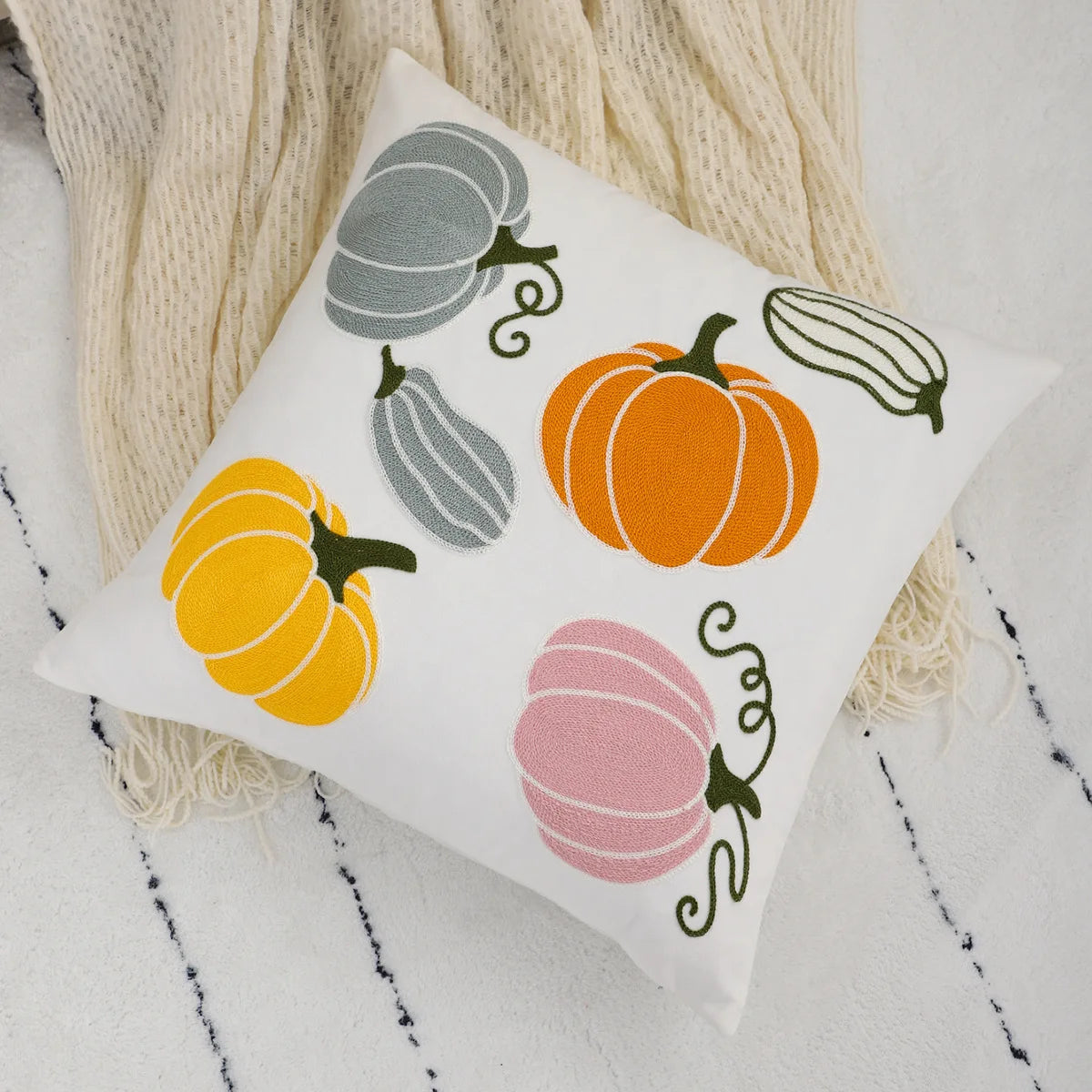 Decorative pillow with pumpkins and gourds on a textured surface