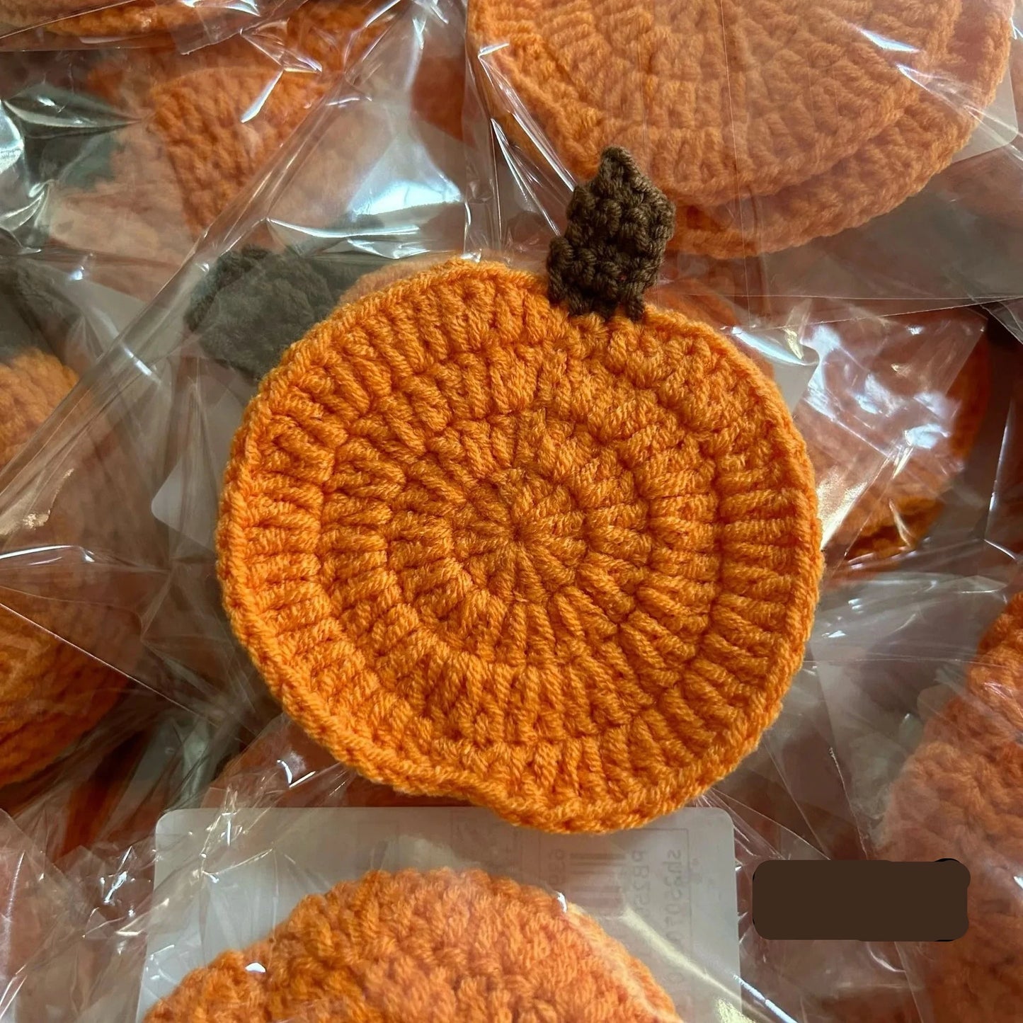 Orange crocheted pumpkin coasters in clear packaging. Handmade crochet pumpkin coaster in cotton, Halloween table decor for mugs and drinks, festive DIY autumn party accessory
