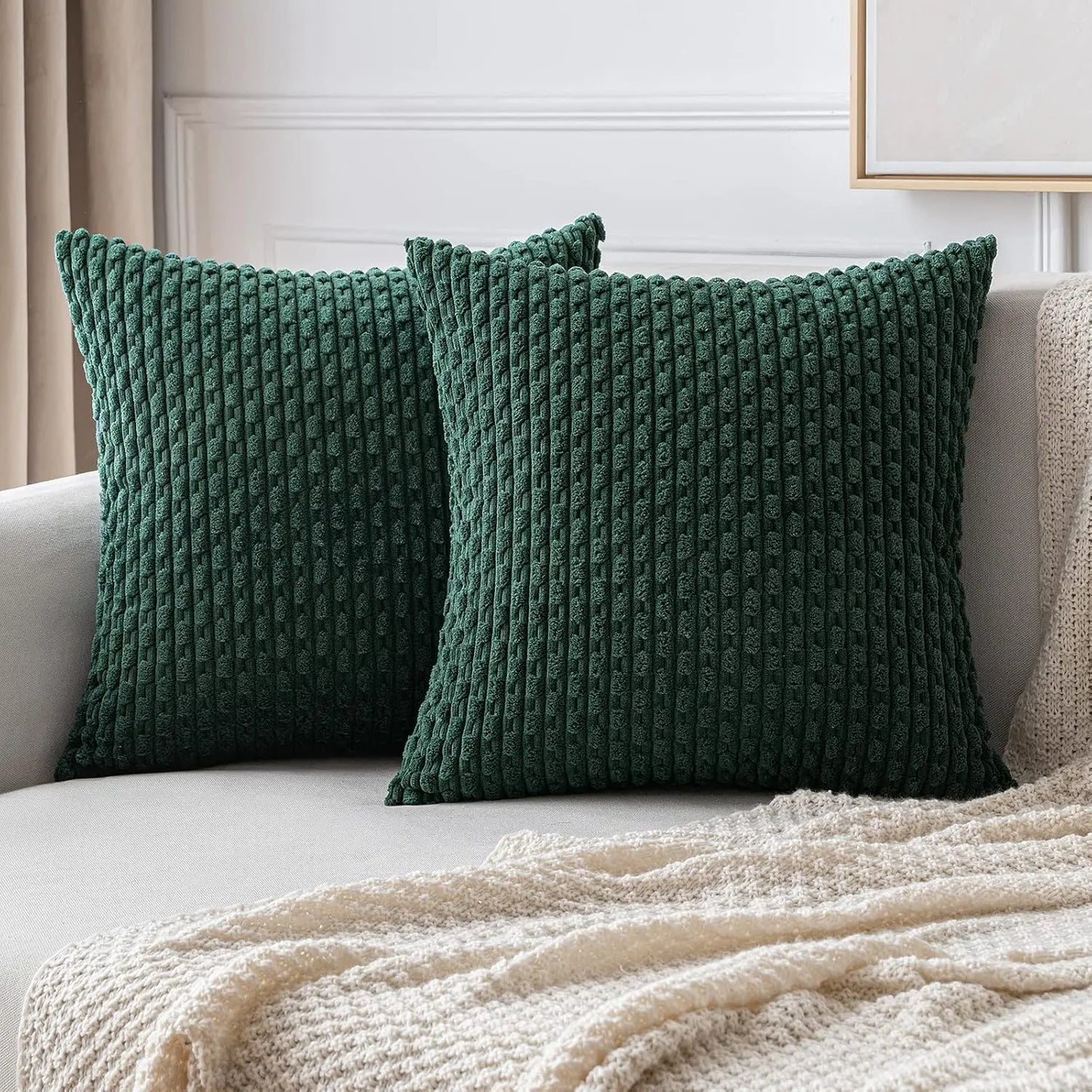 Two green textured pillows on a beige sofa with a beige blanket.