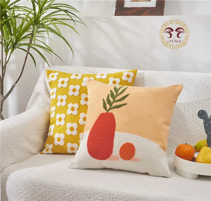 Decorative pillows with a carrot design on a white couch, featuring a plant and small table with fruits in the background.