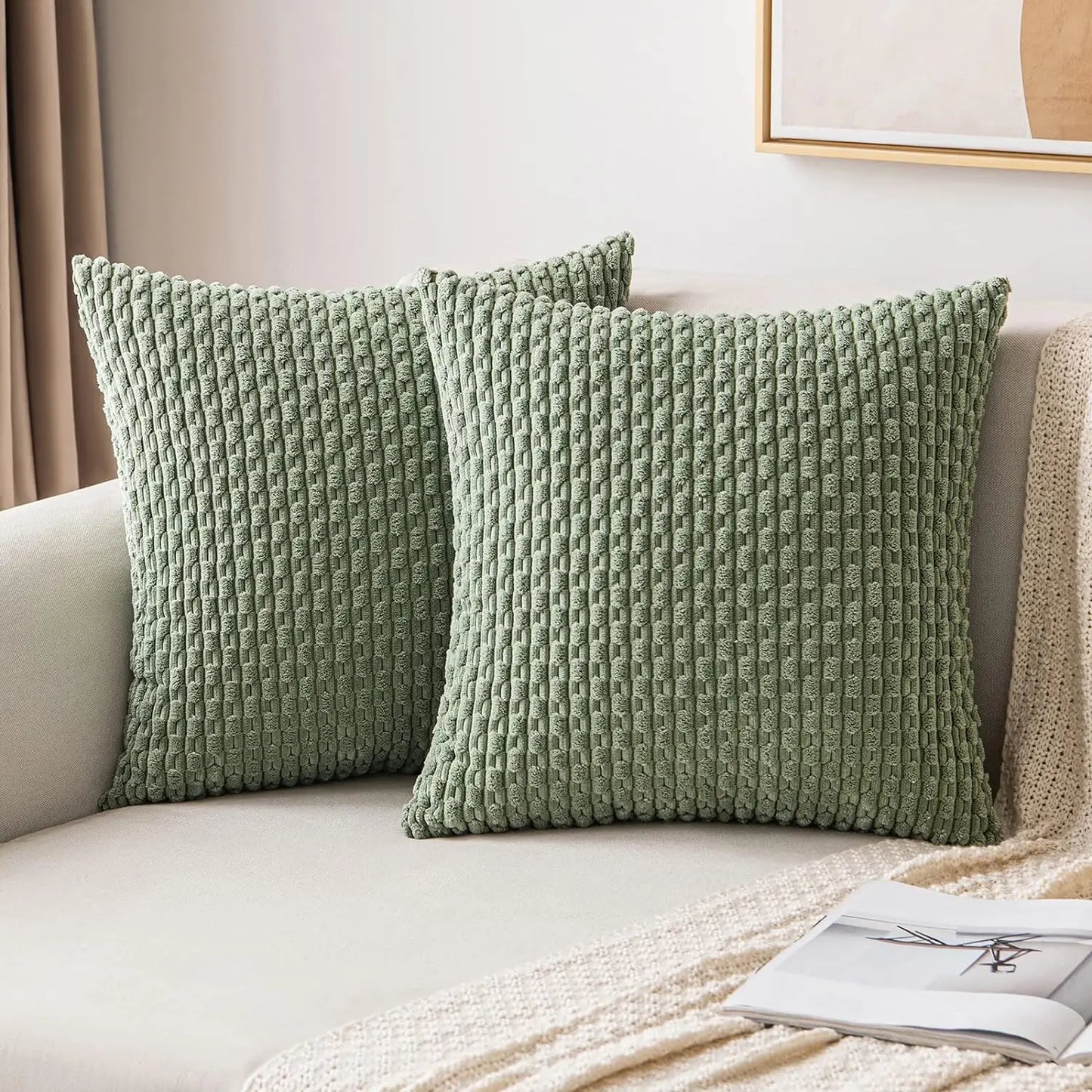 Two sage green textured pillows on a beige sofa with a neutral background