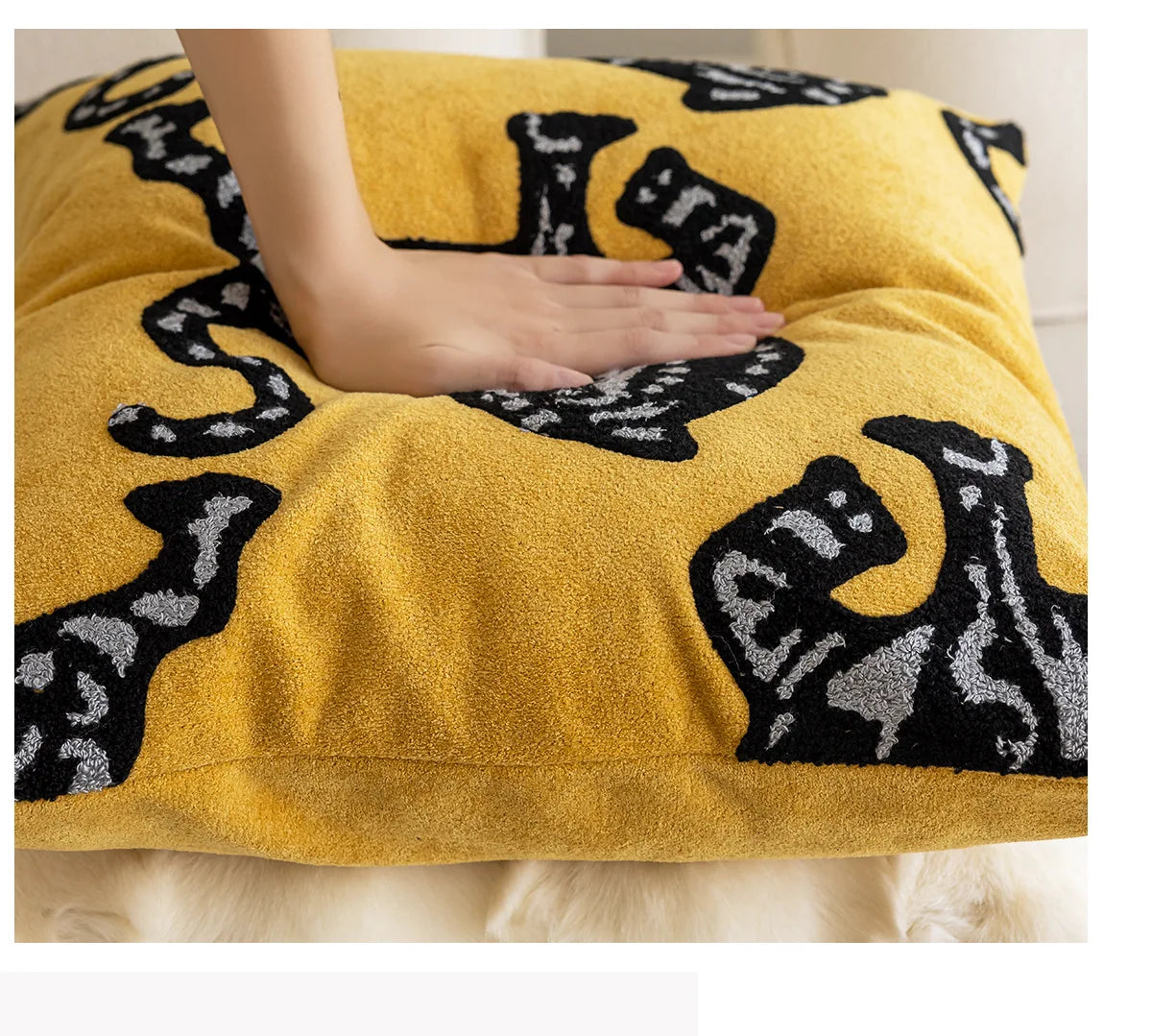 Yellow cushion with black cat patterns on a white surface. Modern minimalist embroidered pillow cover for living room decor.