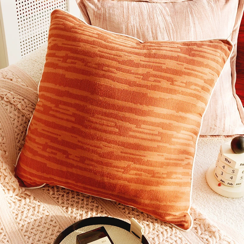Orange textured pillow on a white chair with a blurred background. Boho Home Decor.