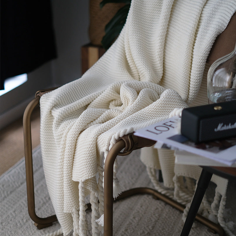 White knitted blanket draped over a chair with a blurred background