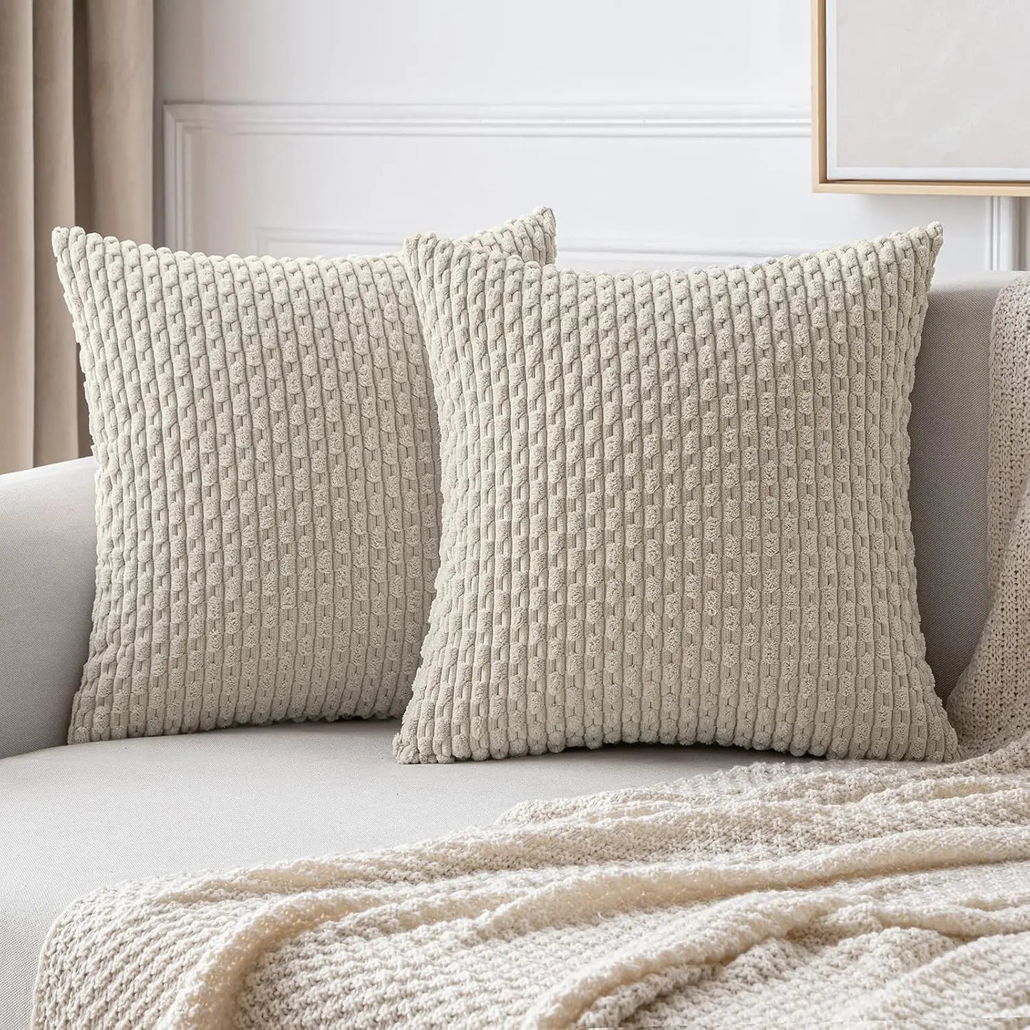 Two textured beige pillows on a sofa with a neutral background