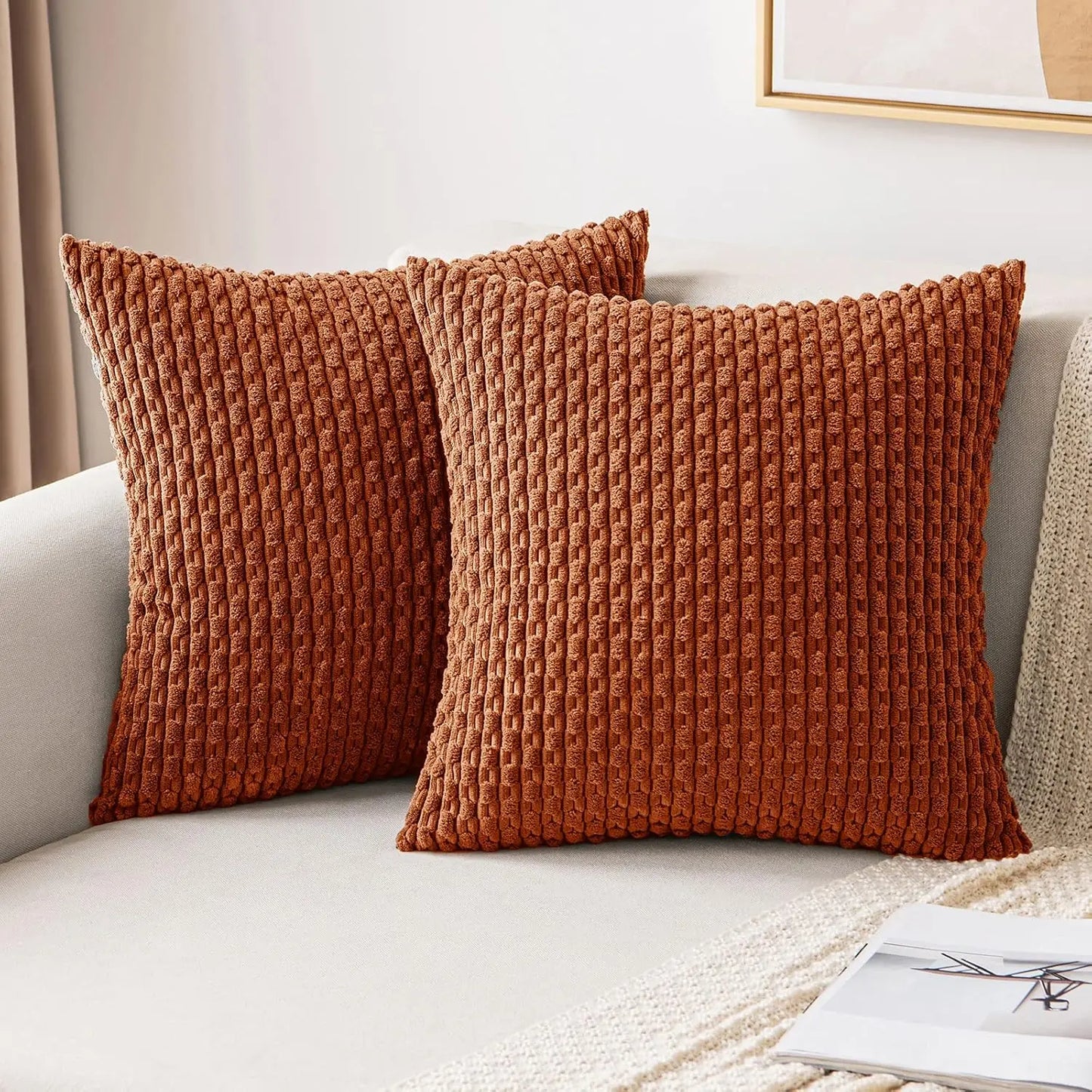 Two brown rust orange textured pillows on a light-colored sofa.