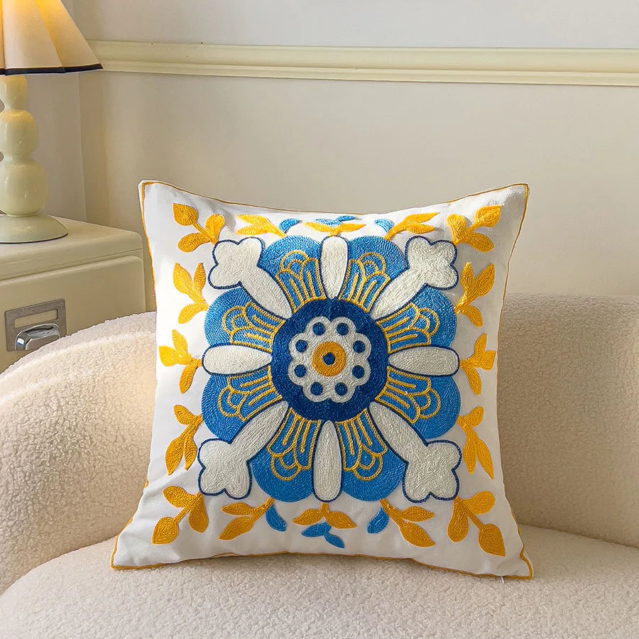 Decorative pillow with blue and yellow floral pattern on a beige couch.