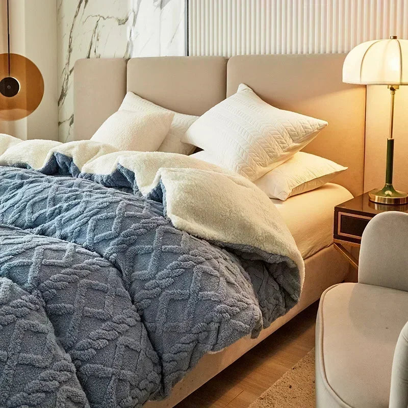 Neatly made bed with blue textured blanket and white pillows in a bedroom setting. Soft plush duvet cover and blanket in solid color with striped jacquard design, dual-use artificial cashmere fleece bedding for cozy winter warmth