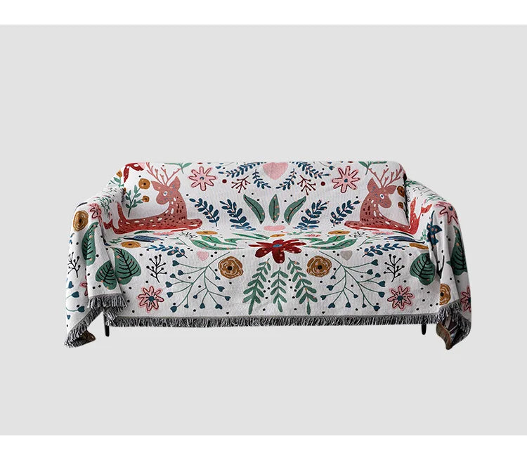 Sofa with a colorful floral and deer patterned throw blanket on a white background. Deer forest jacquard woven blanket with floral and woodland tapestry design – boho throw for sofa or bed, soft cotton blend decorative bedspread for cozy home décor.