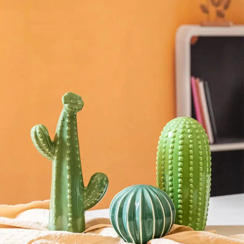 Decorative cacti on a surface with an orange wall in the background. Modern ceramic cactus figurine for home or office decoration. House warming gift.