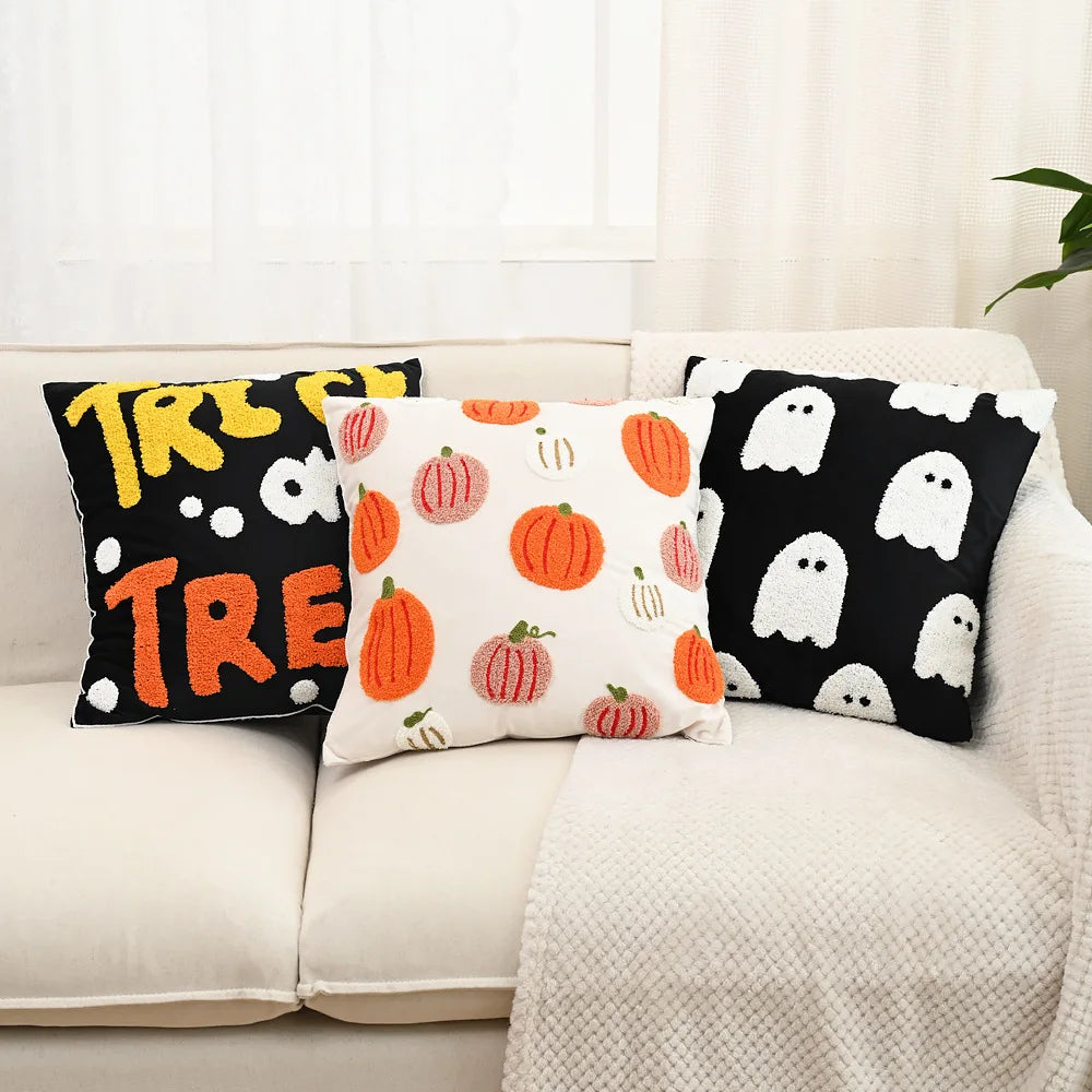 Three Halloween-themed pillows on a couch with pumpkins, ghosts, and 'Treat' text.