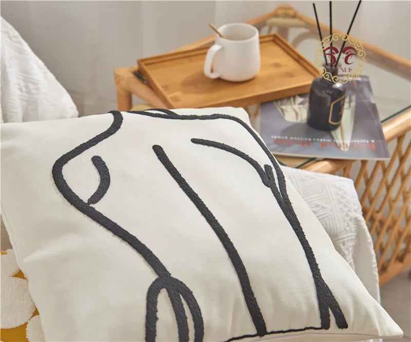 Decorative pillow with black abstract design on a white background, placed on a chair.