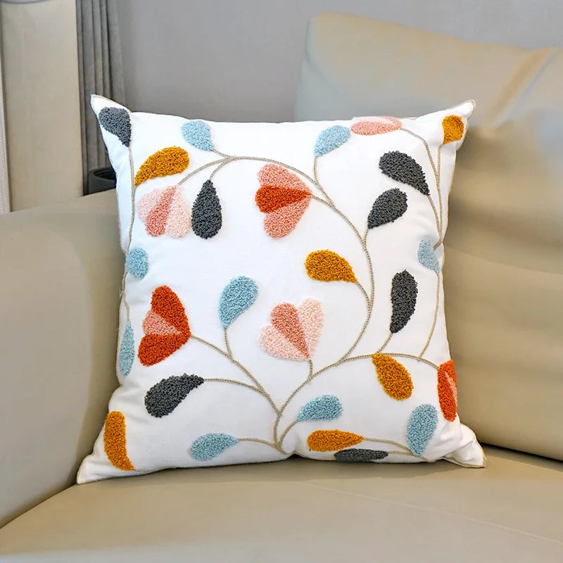 Decorative pillow with colorful leaf pattern on a beige sofa. Floral embroidered throw pillow cover boho decor