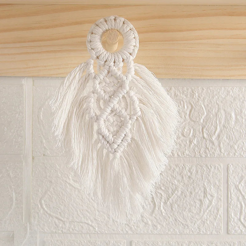 Macrame wall hanging with tassels on a textured white wall.