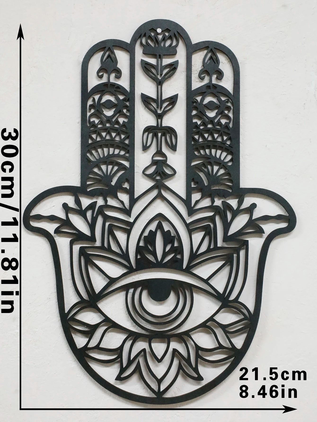 Black hamsa hand-shaped wood wall decor with protective evil eye, photographed against neutral background for alternative boho room styling.