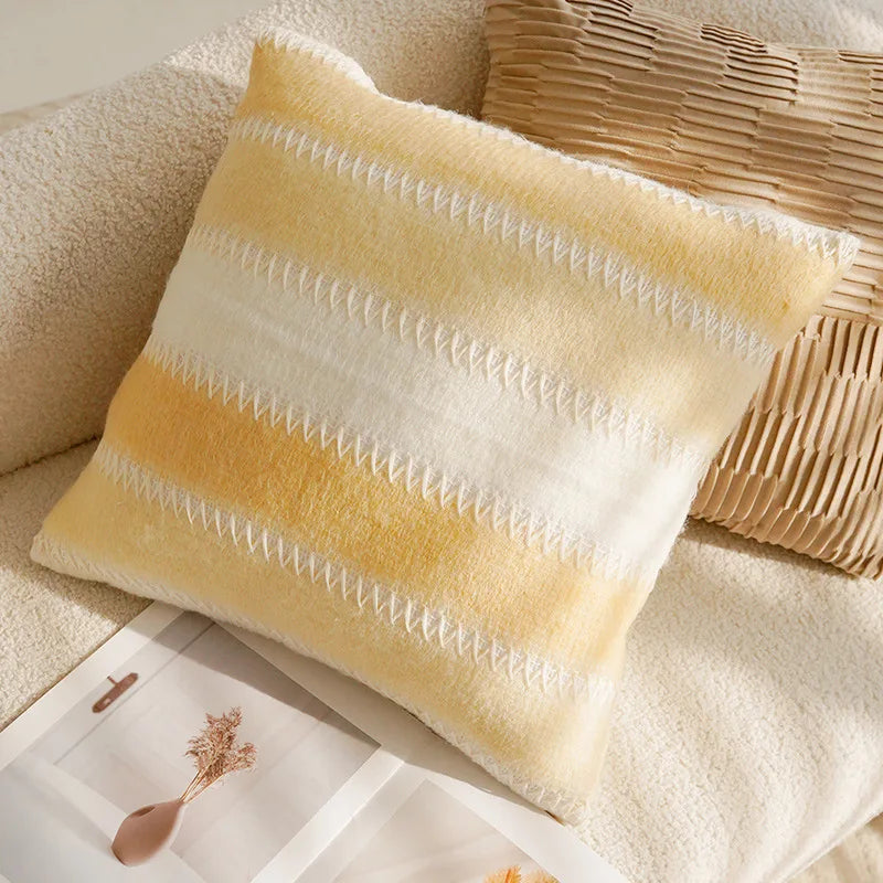 Yellow and white striped pillow on a beige couch with a woven basket.
