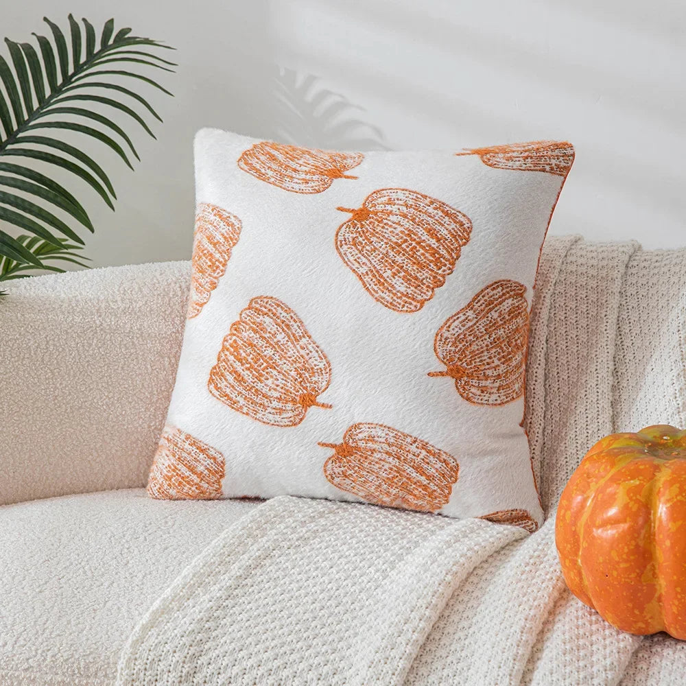 Decorative pillow with pumpkin pattern on a couch next to a small pumpkin. Cozy fall pumpkin pillow cover for living room or bedroom