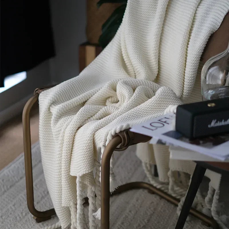 White knitted blanket draped over a chair with a blurred background