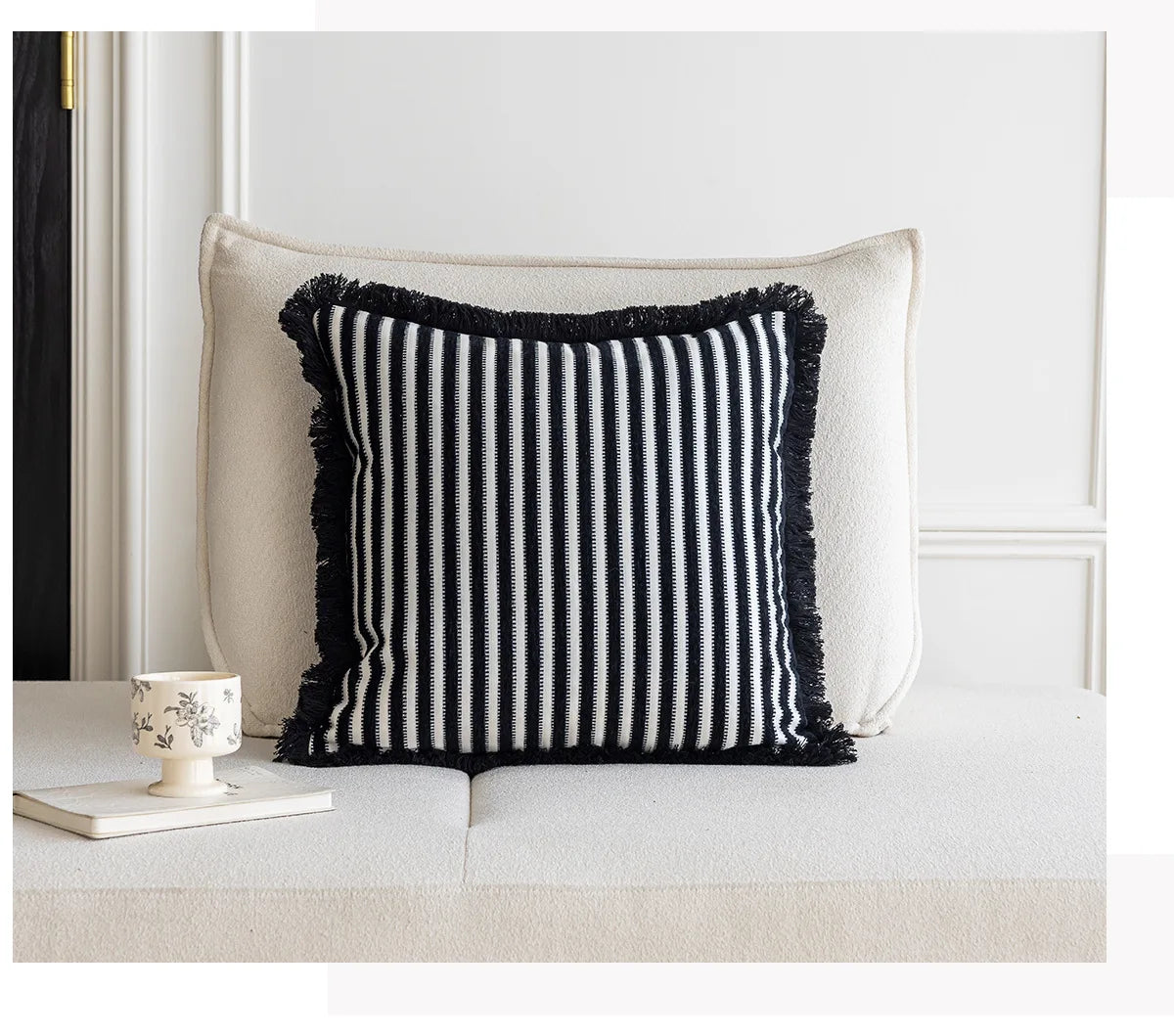 Black and white striped pillow with frayed edges on a neutral background. Modern minimalist embroidered pillow cover for living room decor.