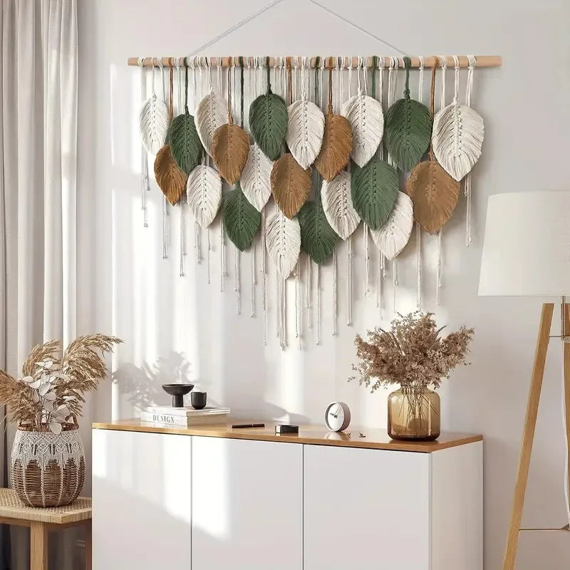Decorative wall hanging with leaf patterns in a room with a white cabinet and lamp.