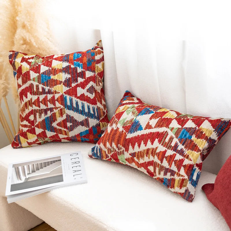 Colorful patterned pillows on a white couch with a magazine underneath. Bohemian Aztec woven pillow cover, geometric jacquard cushion for sofa, bed, or living room decor in neutral cotton blend fabric.