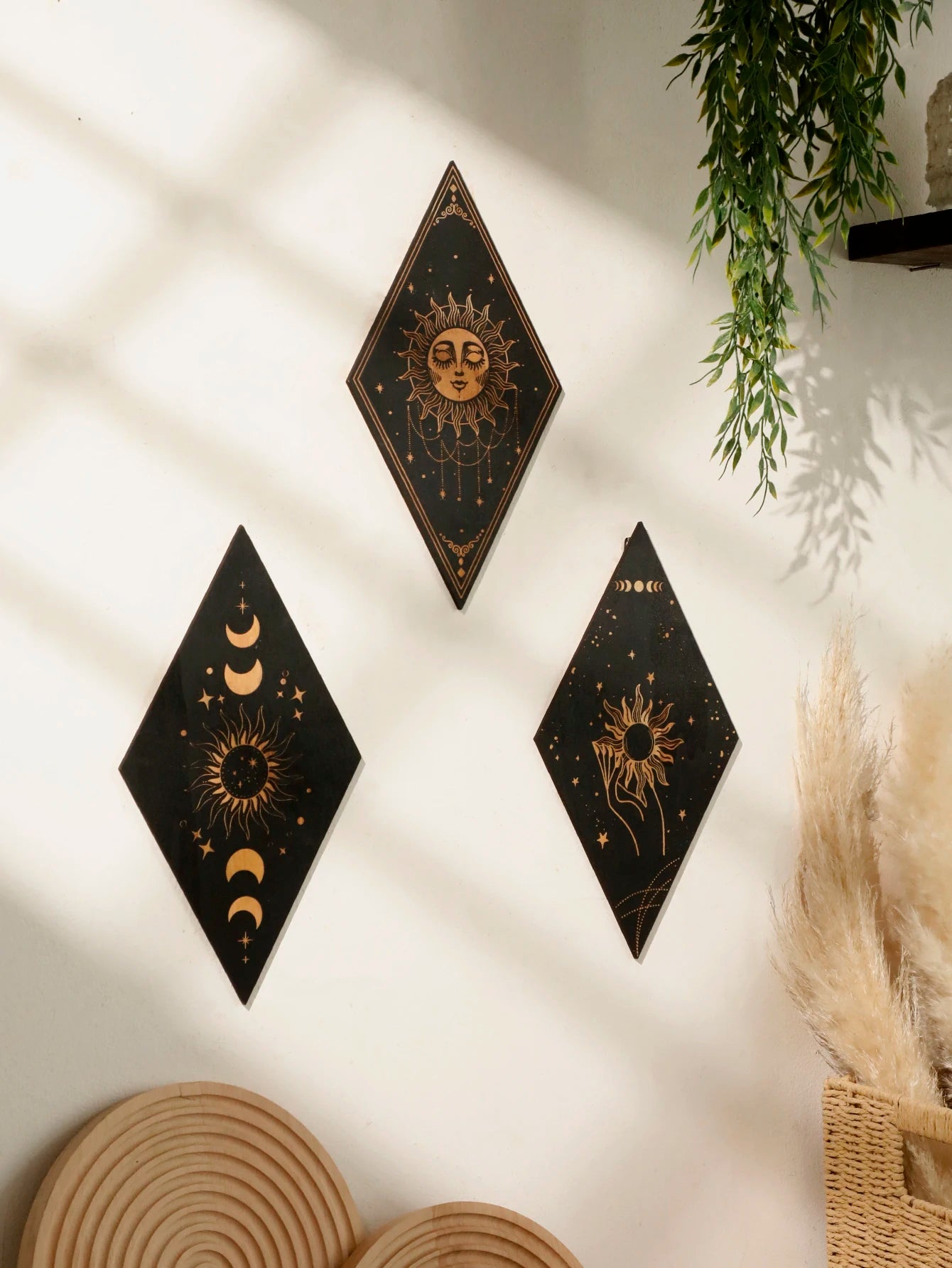 Three diamond-shaped wall art pieces with celestial designs on a white wall. boho home decor, wooden witchy wall hanging, moon phase wall art, gothic home decor, celestial wall pediment, snake wall hanging, sun and moon wall decor, spiritual home accents, mystical bedroom art, witchy housewarming gift