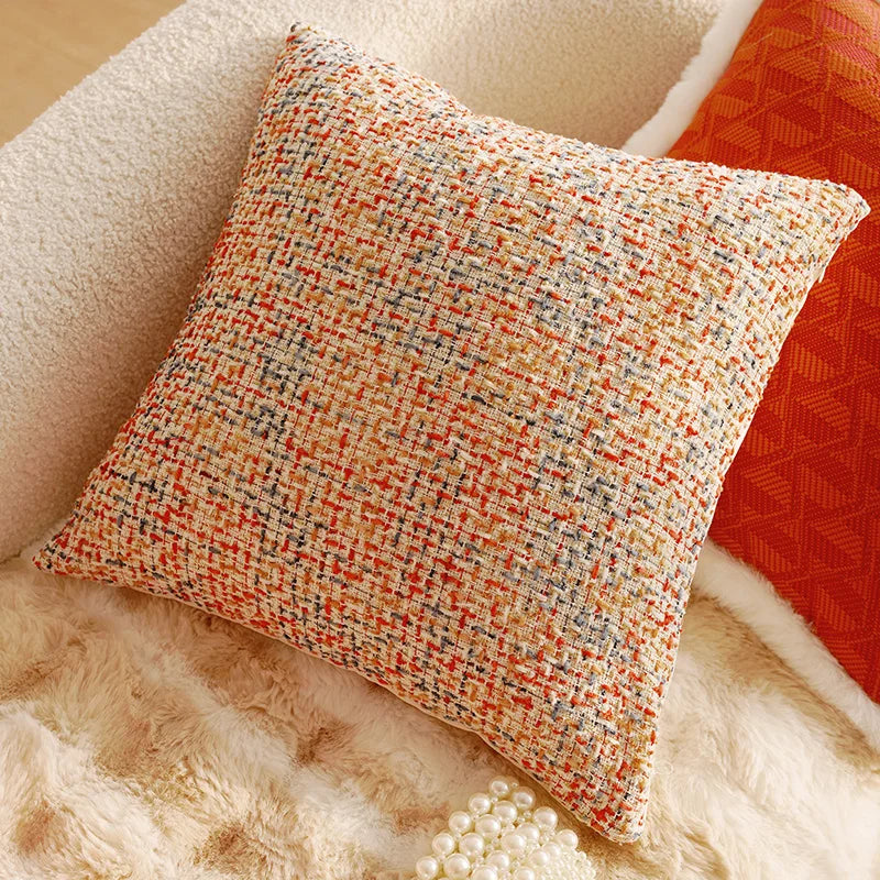 Textured pillow with orange and beige pattern on a soft surface. Boho Home Decor.