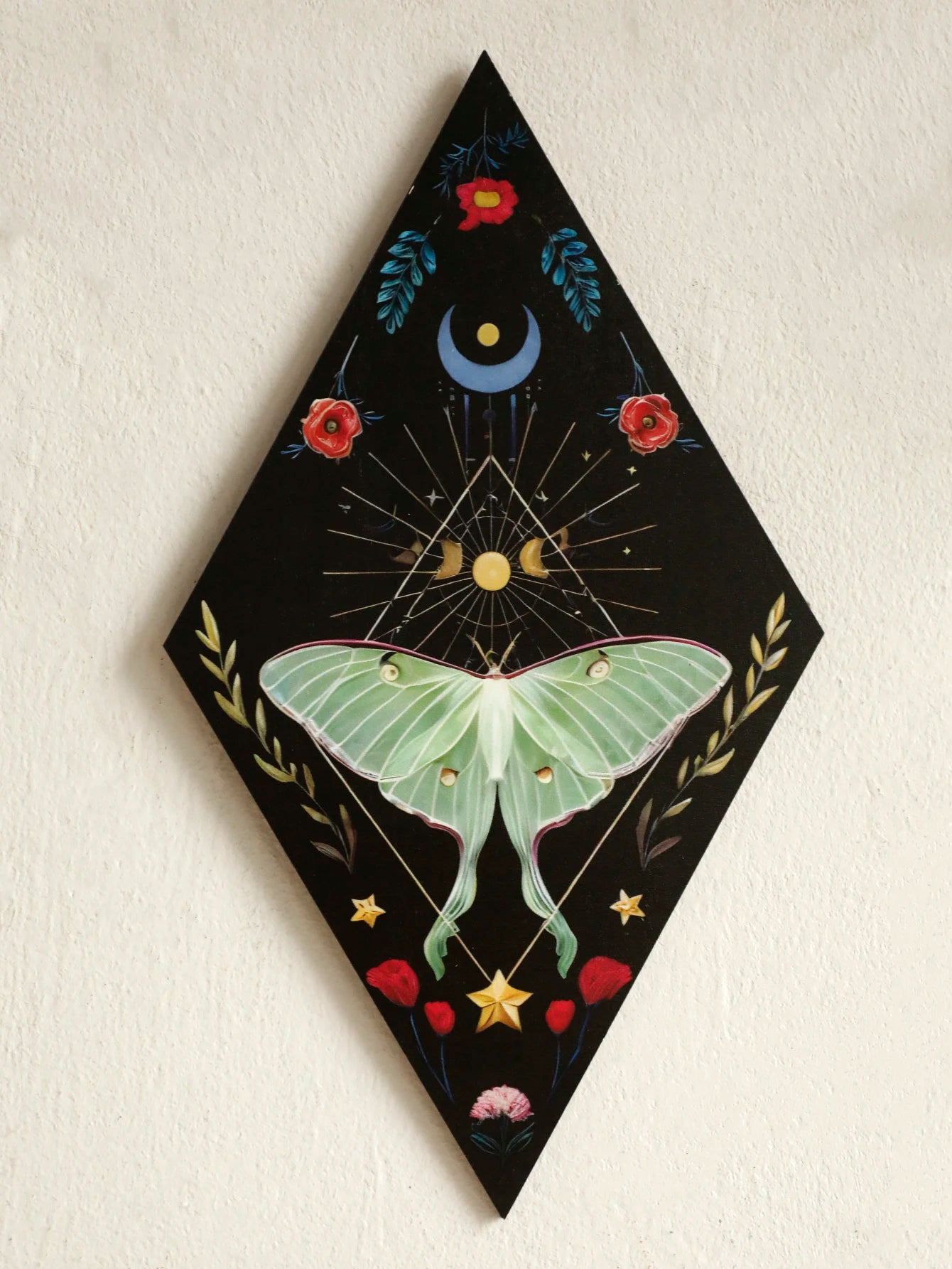 Decorative wall art with a green butterfly, flowers, and celestial elements on a black background. Rustic colorful wood wall art panel with moon, stars, and butterfly engraving, displayed above a sofa in a boho-styled living room