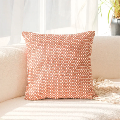 Coral patterned pillow on a beige couch with a light background