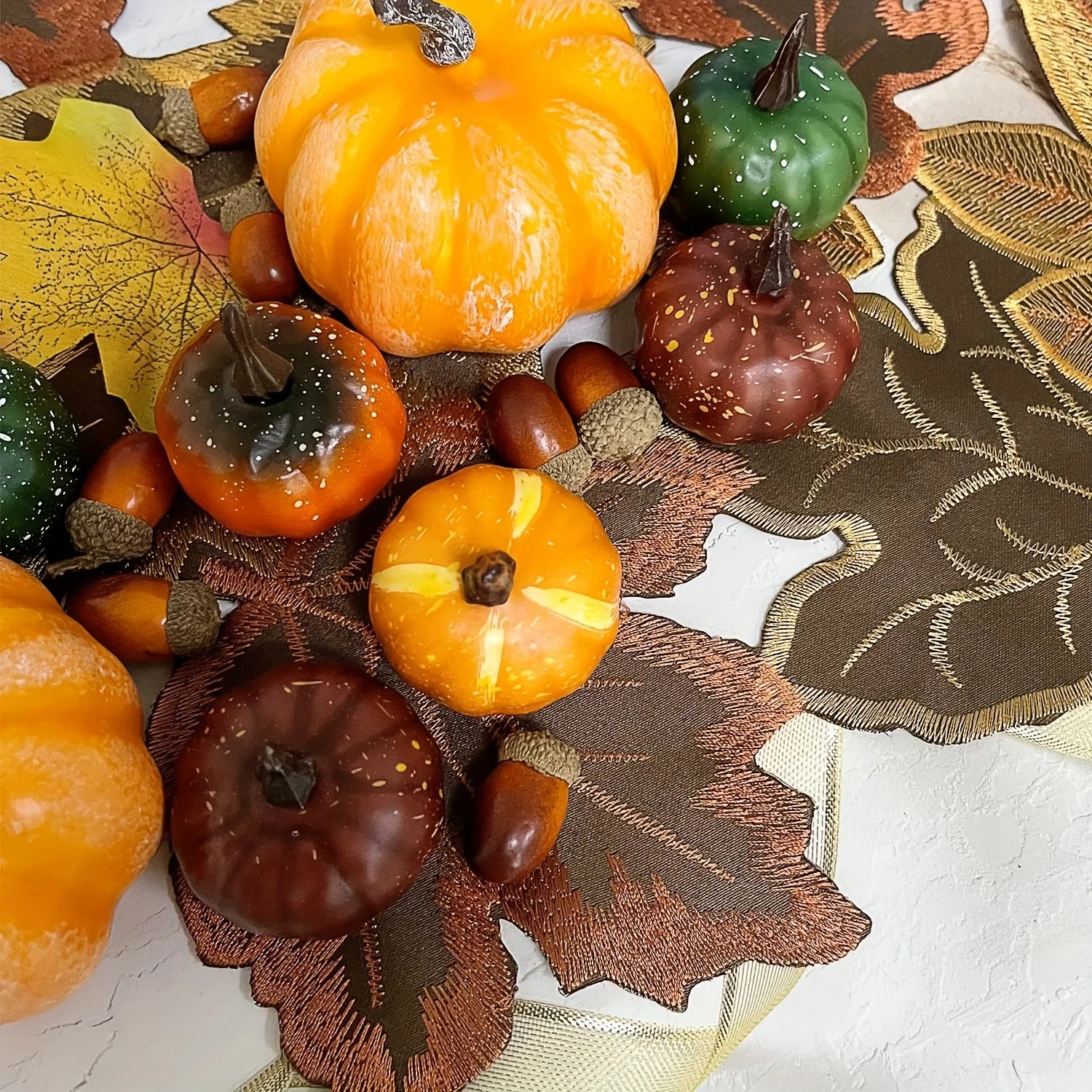 Decorative wreath with pumpkins, leaves, and acorns on a textured surface
