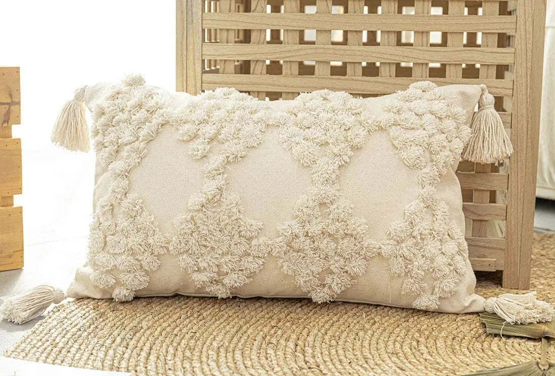 Decorative pillow with floral patterns and tassels on a wooden surface