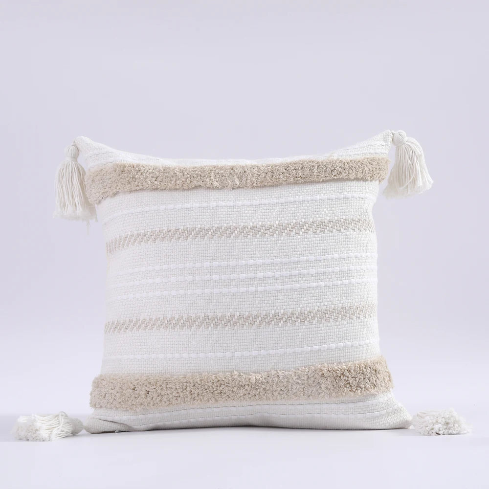 Decorative pillow with striped pattern and tassels on a light gray background