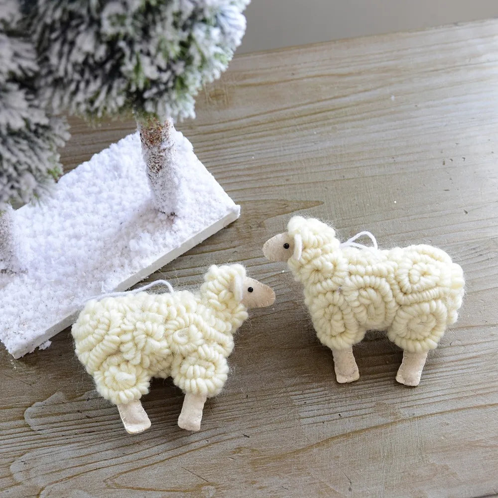 Two white sheep ornaments on a wooden surface with a decorative background.