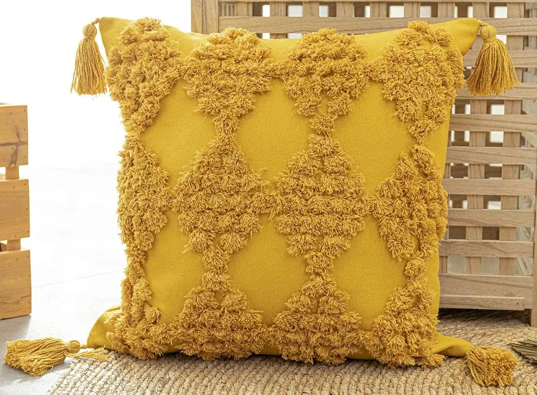 Yellow pillow with tassels on a wooden surface