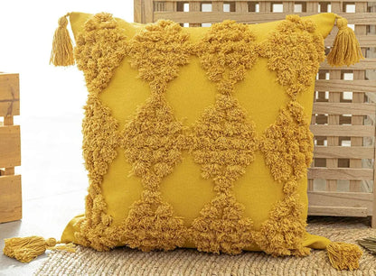 Yellow pillow with tassels on a wooden surface