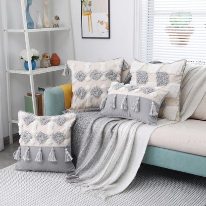 Living room with a sofa adorned with patterned cushions and a blanket, next to a white shelf.