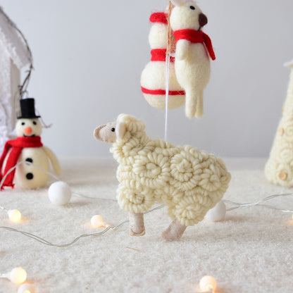 Knitted sheep and snowman decorations on a white surface with string lights.