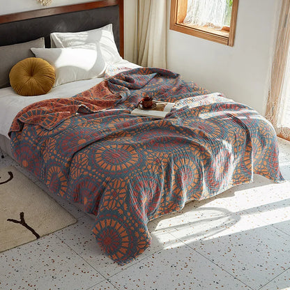 Bed with a patterned quilt in a bright bedroom. Bohemian cotton gauze quilted bedspread in 4-layer muslin, breathable summer blanket for bed or sofa, lightweight soft throw in assorted colors and patterns. My Boho Home. 