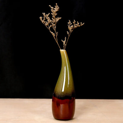 Green and brown boho vase with dried branches on a black background