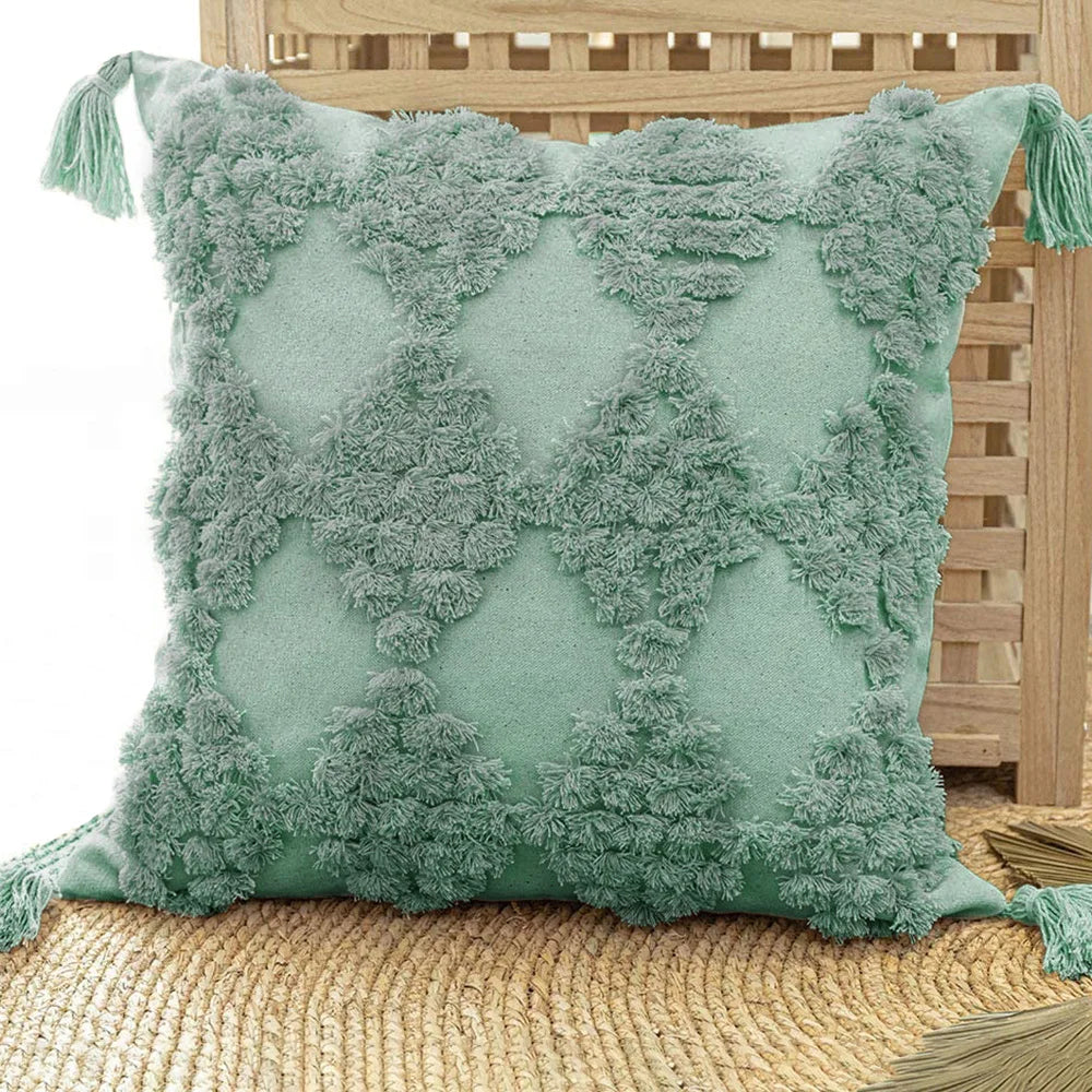 Mint green textured pillow with tassels on a wooden chair.