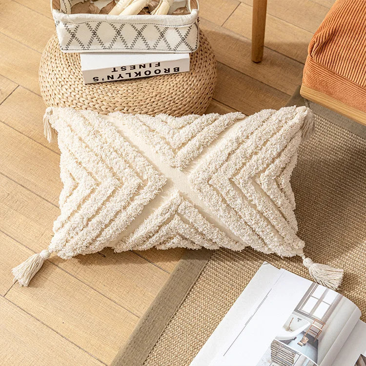 Beige textured pillow on a wooden floor with a basket and books in the background