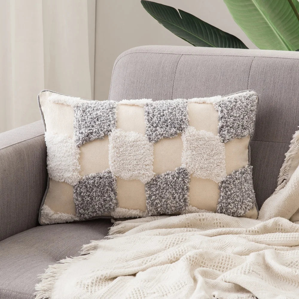 Decorative pillow with a checkered pattern on a gray sofa with a plant in the background
