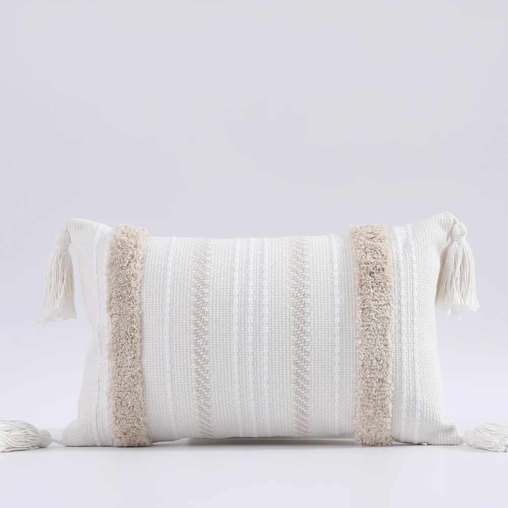Decorative pillow with textured patterns and tassels on a light gray background